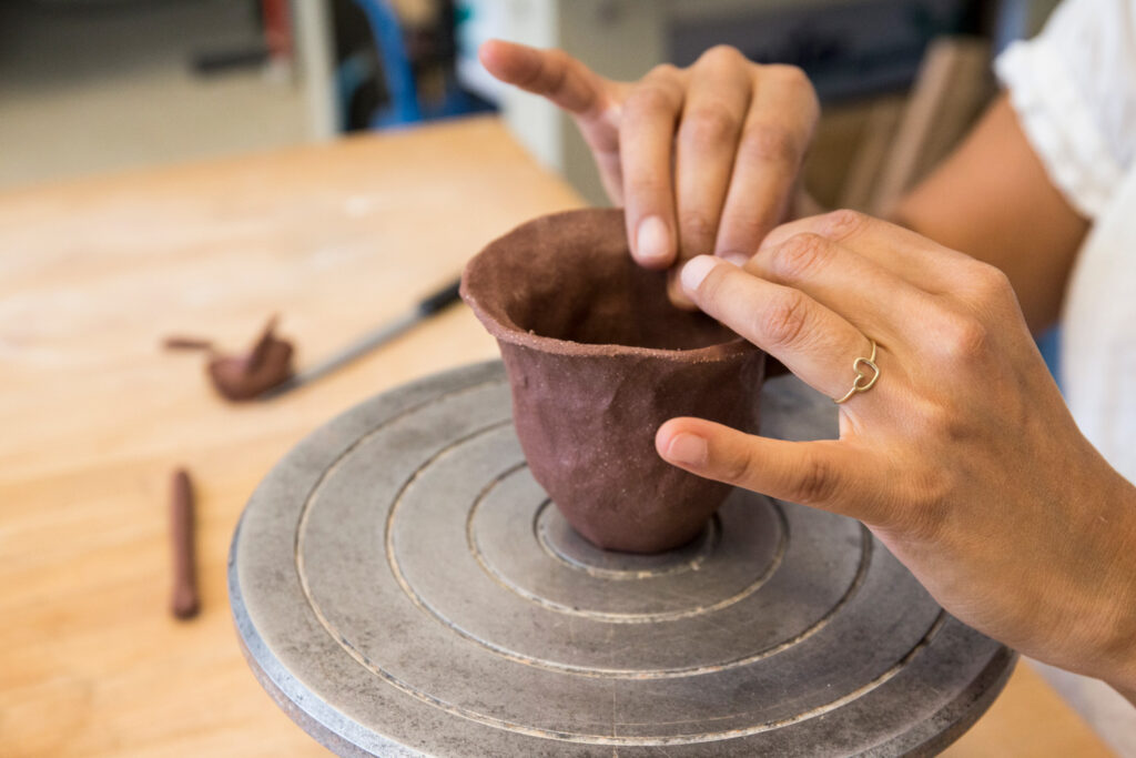 Woman shaping a clay cup with her hands