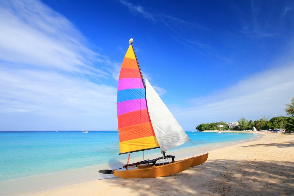 Rainbow striped sailboat on golden beach, with vibrant blue sky in the background