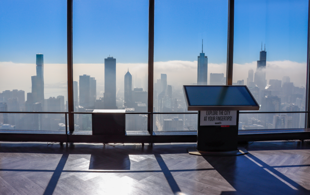 A viewing deck with floor to ceiling windows showing a city skyline