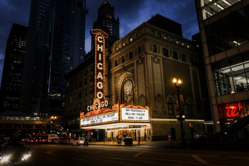 A view by night of a classical theatre building illuminated by lighted signs