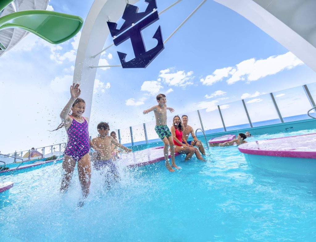 Children and parents having fun in the pool of a cruise ship, with blue skies behind them