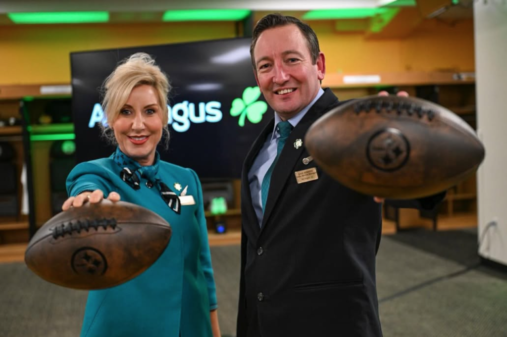 A woman and a man in cabin crew uniform holding American footballs toward the camera