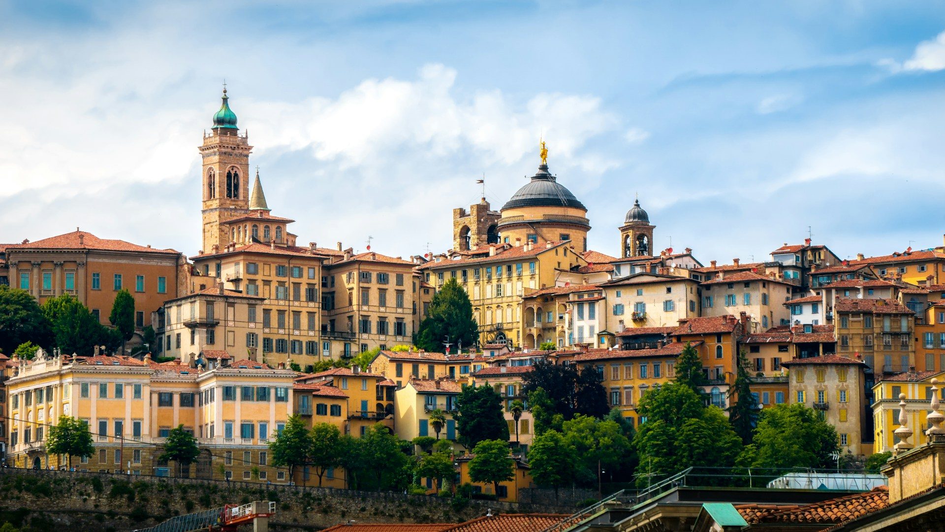 A view of the rooftops and historic buildings of Bergamo, with blue sky in background