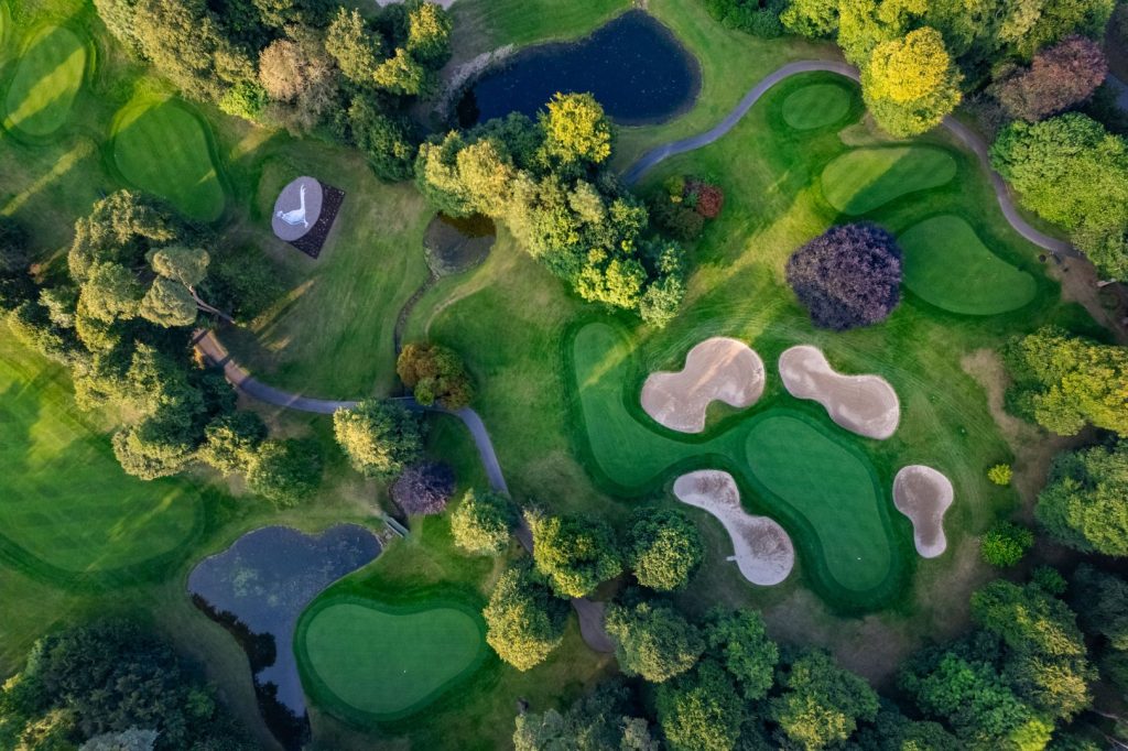 Aerial view of a golf course with areas of forest, sand and lawn
