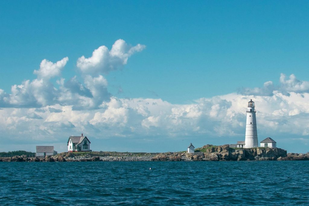 An island with a white lighthouse, blue sea and blue sky