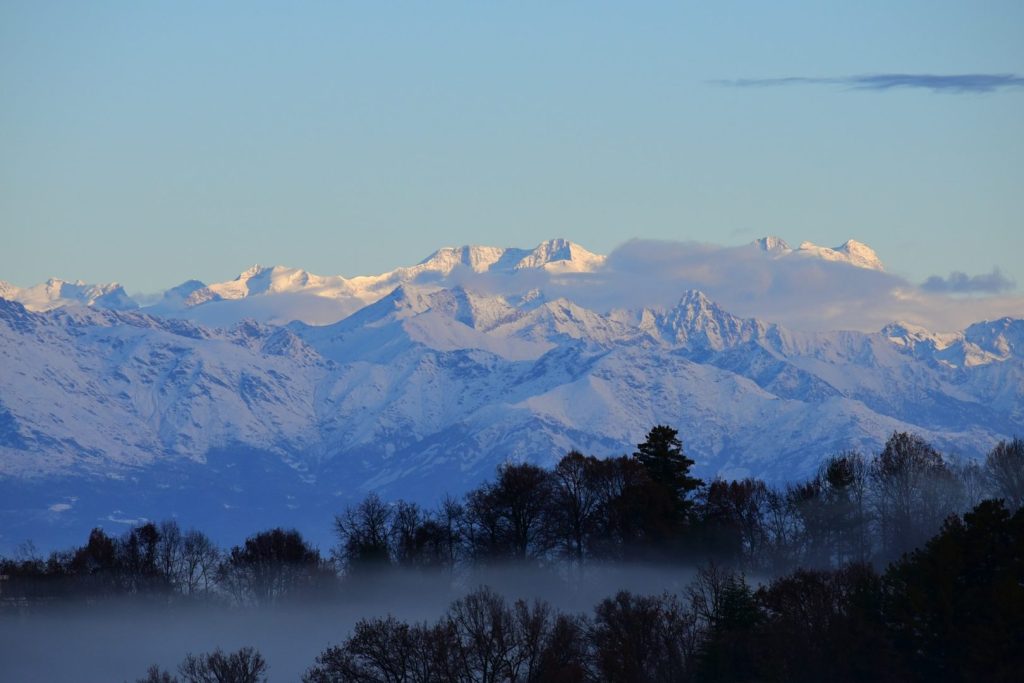 A view of snow covered mountains with hills in foreground