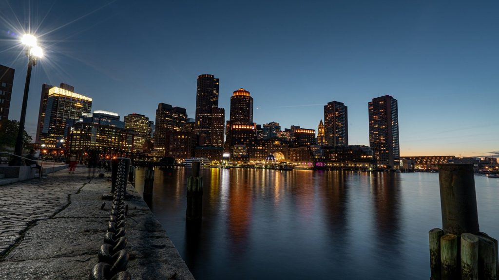 Boston's skyline by night - skyscrapers and lights with water in foreground