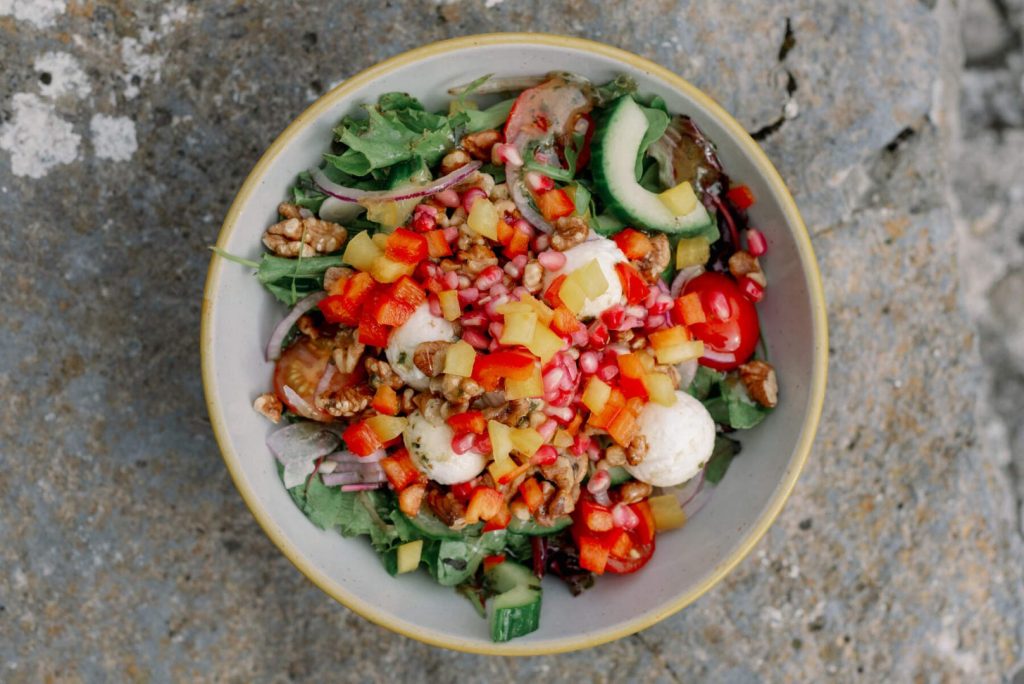 Colourful plate of food with pomegranate seeds, vegetables and walnuts