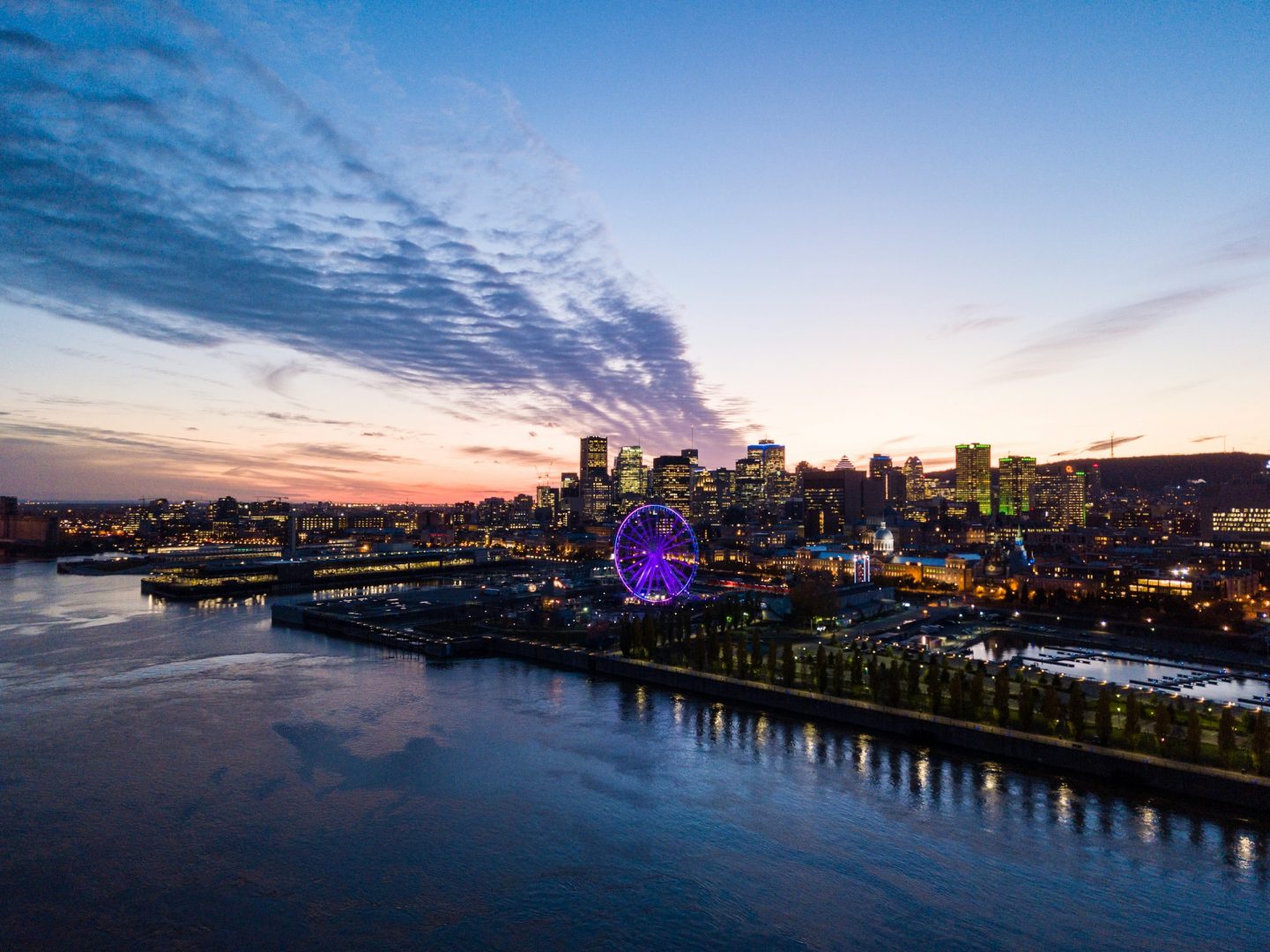 Aerial view of a city skyline at twilight, with pink and blue sky