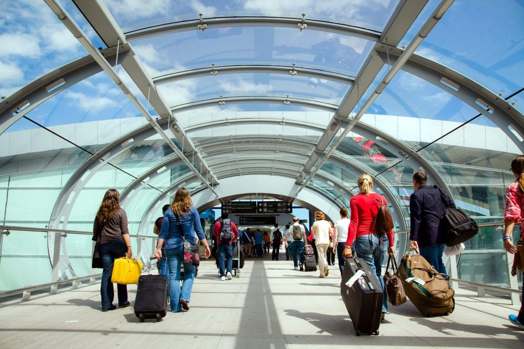 People leaving T2 via the glass walkway on a sunny day