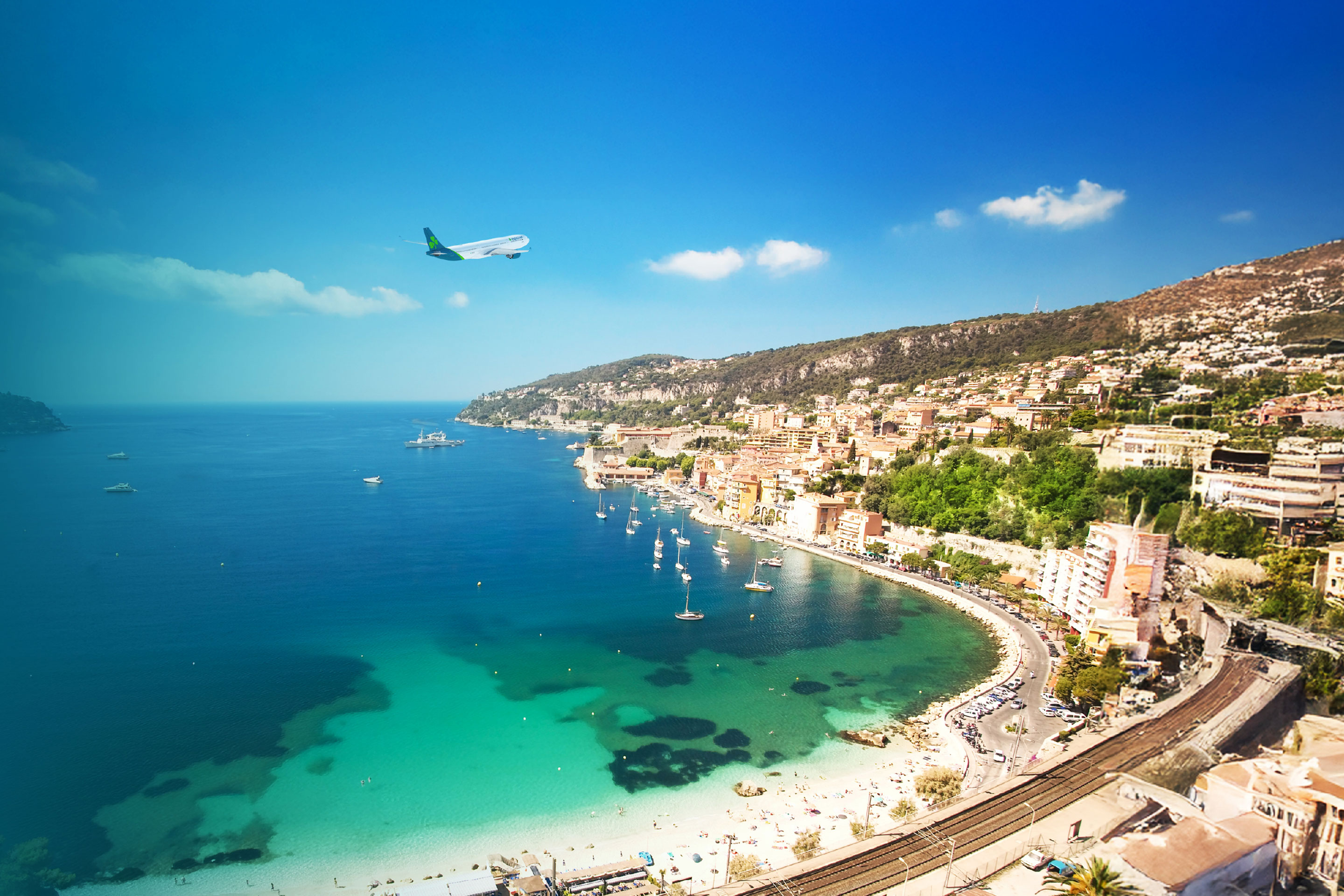 Aer Lingus plane flying above coastline of Nice, France on a bright, sunny day