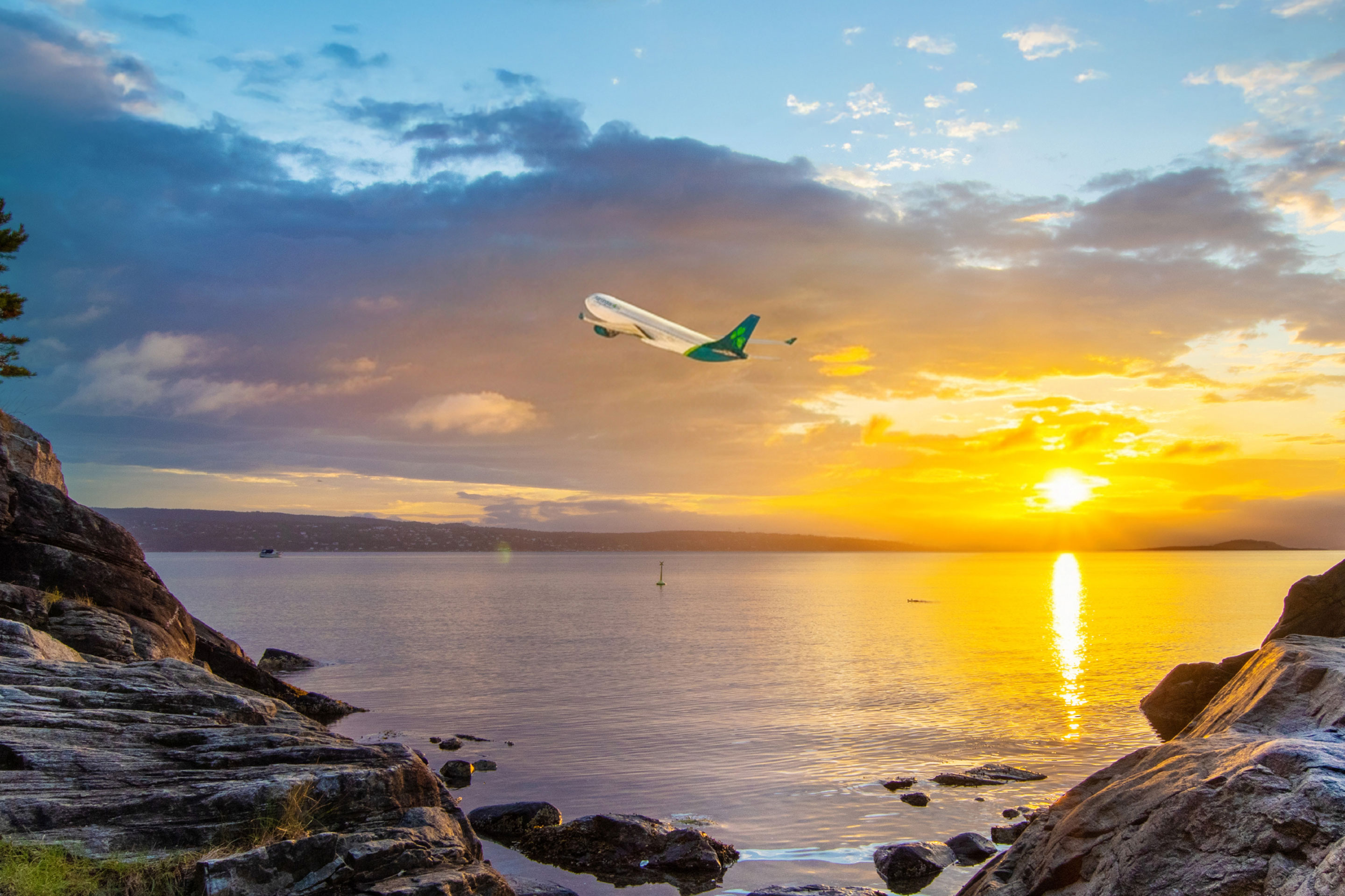 Aer Lingus plane flying over Fjord in Oslo, Norway at sunset