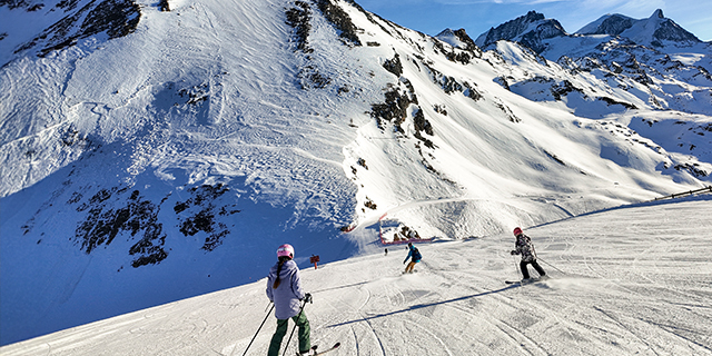 Family of three skis down slope at ski resort