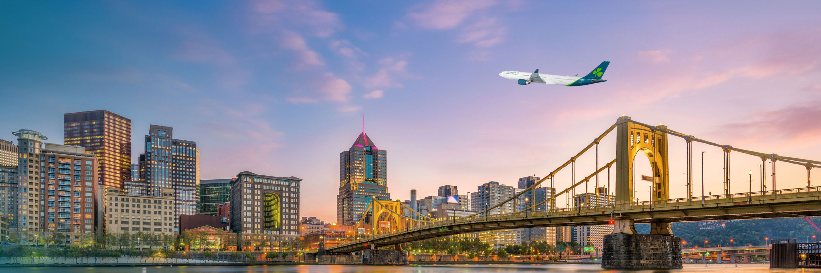 Aer Lingus plane flying above skyline of Pittsburgh City at Dusk