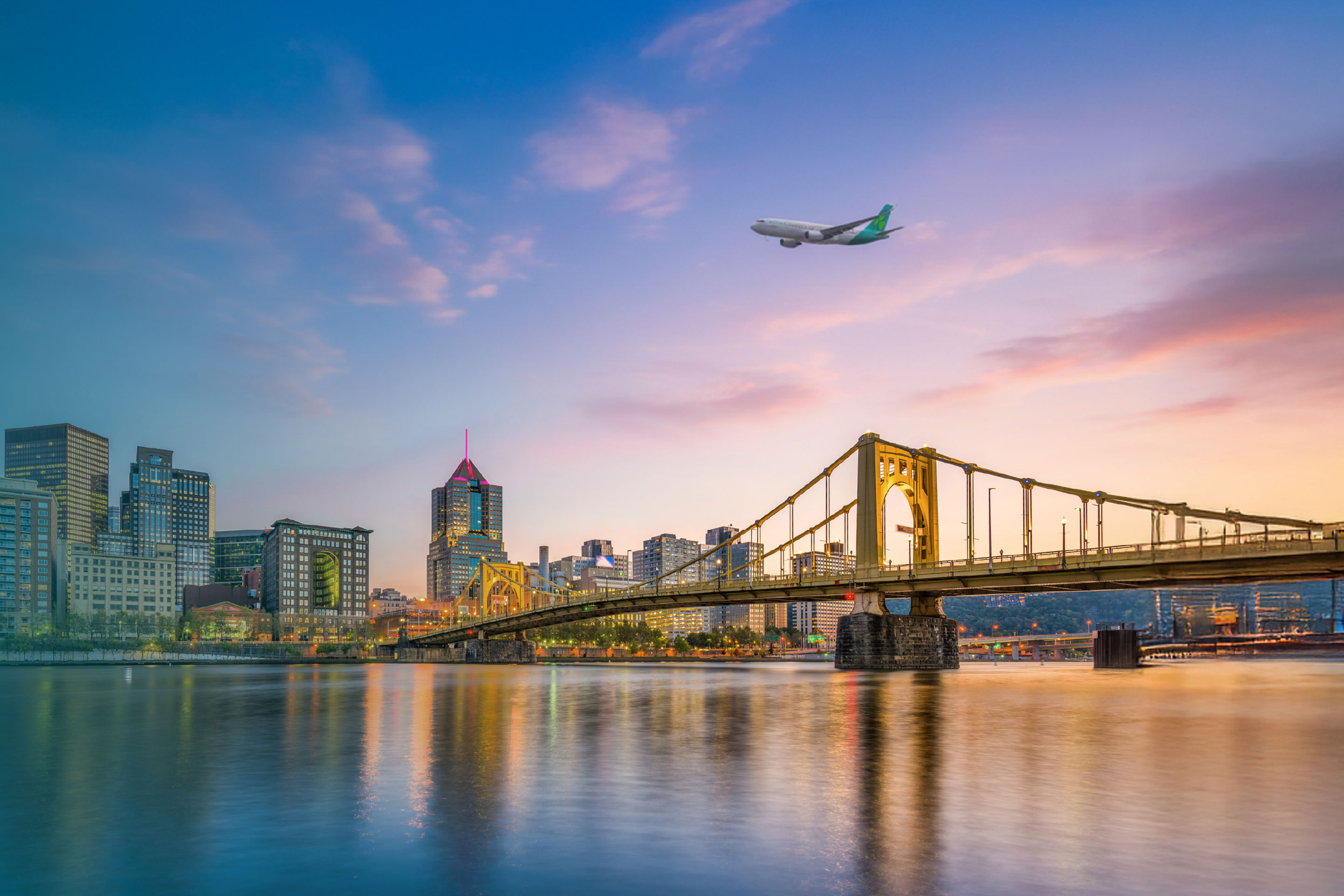 Aer Lingus plane flying above skyline of Pittsburgh City at Dusk